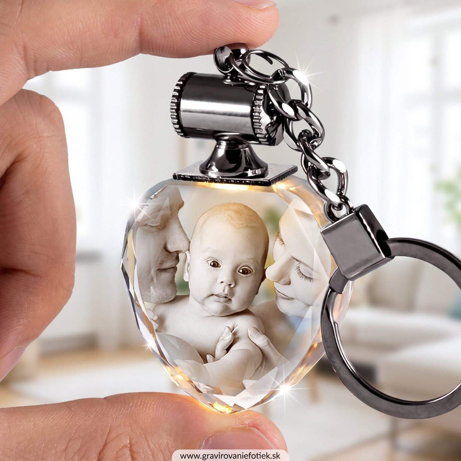 Close-up of a finger pinching a faceted crystal pendant containing black-and-white baby photos, on a silver chain.