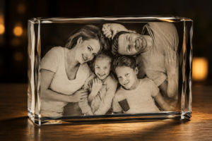 Black-and-white family portrait (mom, dad, son, daughter) in a clear crystal photo frame on a wooden table.