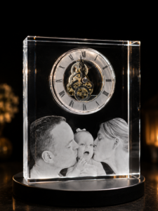 Crystal-block keepsake clock with visible gears, featuring a black-and-white photo of a couple kissing their baby on a round base.