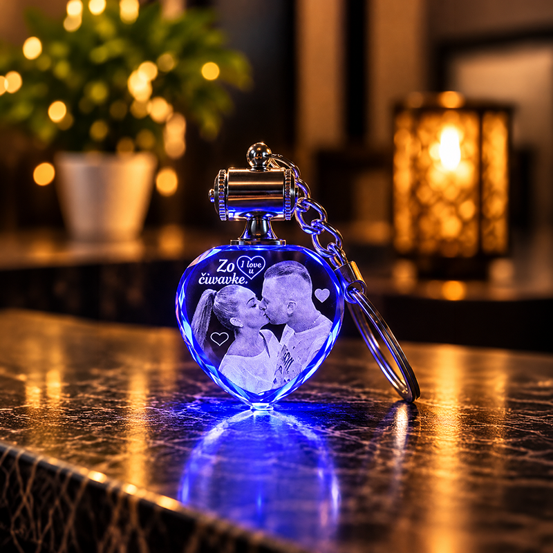 Blue heart-shaped LED keychain with a photo of a couple kissing, placed on a marble surface with warm background lights.